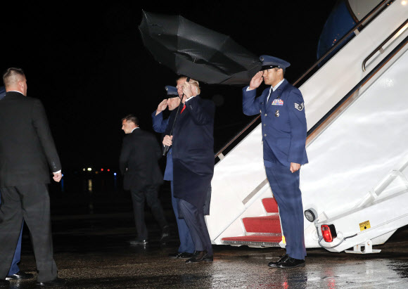 도널드 트럼프 미국 대통령이 28일(현지시간) 미국 워싱턴의 DC 앤드루스 공군 기지에 도착해 미국 대통령 전용기 에어 포스 원에서 내려오고 있는데 강풍에 우산이 뒤집어지고 있다. AP 연합뉴스