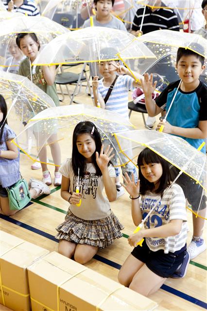 초등학교 학생들이 현대모비스가 매년 10만개씩 무료 배포하는 투명 우산을 쓰고 있는 모습. 현대모비스 제공