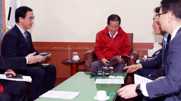 자유한국당 홍준표 대표가 30일 오후 서울 여의도 당사에서 4.27 남북정상회담 관련 현안보고를 위해 방문한 조명균 통일부 장관과 인사 후 자리에 앉고 있다.  연합뉴스