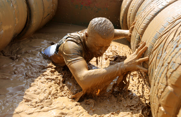 1일(현지시간) 벨라루스의 민스크에서 열린 ‘Bison race’ 익스트림 런에 참여한 참가자들이 진흙을 통과하고 있다. EPA 연합뉴스