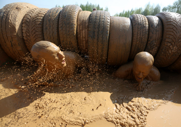 1일(현지시간) 벨라루스의 민스크에서 열린 ‘Bison race’ 익스트림 런에 참여한 참가자들이 진흙을 통과하고 있다. EPA 연합뉴스