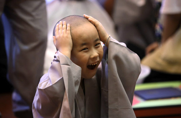 한 동자승이 2일(현지시간) 서울 종로구 조계사에서 부처님오신날을 앞두고 삭발한 머리를 만지며 웃고 있다. AP 연합뉴스