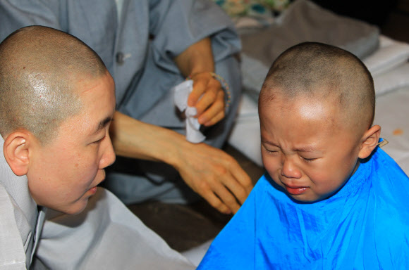 부처님 오신 날을 앞두고 3일 설악산 신흥사에서 열린 동자승 단기출가 수계법회에 참가한 한 어린이가 삭발 도중 눈물을 글썽이고 있다.  연합뉴스