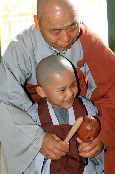 부처님 오신 날을 앞두고 3일 설악산 신흥사에서 열린 동자승 단기출가 수계법회에 참가한 한 동자승에게 스님이 목탁 치는 법을 가르쳐 주고 있다.  연합뉴스