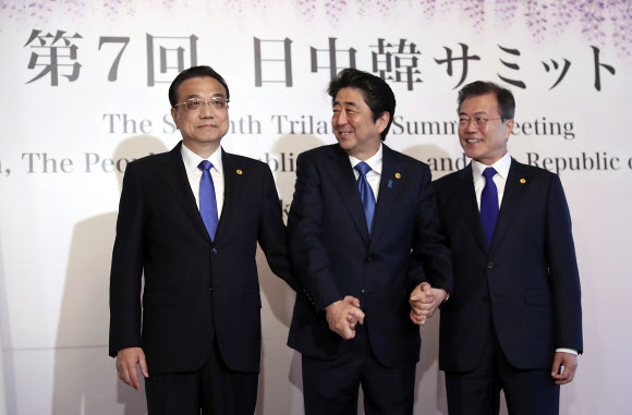 문재인 대통령(오른쪽)과 아베 신조 일본 총리(가운데)가 9일 오전 일본 도쿄 ‘하고로모노마’에서 열린 한·일·중 정상회의에 앞서 기념 촬영을 하던 중 리커창 중국 국무원 총리를 동시에 바라보며 미소 짓고 있다.  AP 연합뉴스