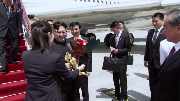 북한 조선중앙TV가 9일 오후 방영한 김정은 국무위원장의 중국 랴오닝(遼寧)성 다롄(大連) 방문 영상에서 김 위원장이 다롄 도착 후 중국 측으로부터 받은 꽃다발을 김여정 당 제1부부장이 건네받고 있다.  연합뉴스