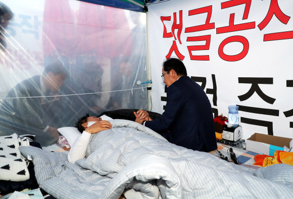 자유한국당 홍준표 대표가 9일 오후 ’드루킹’특검을 요구하며 7일째 국회 앞에서 단식농성 중인 김성태 원내대표를 찾아 병원으로 가자며 설득하고 있다.  연합뉴스