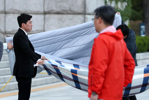 자유한국당 당직자들이 9일 오후 ’드루킹’특검을 요구하며 7일째 국회 앞에서 단식농성 중인 김성태 원내대표의 침구류에 먼지를 털어내고 있다.  연합뉴스