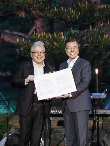 10일 오후 문재인 대통령과 김정숙 여사는 취임 1주년을 맞아 청와대 인근 주민들을 초대해 ”달빛이 흐른다”라는 작은 음악회를 가졌다. 이 음악회에서 문 대통령이 작곡가 김형석씨에게 ‘Mr. President’ 초벌 악보를 선물받고 있다. 청와대 제공