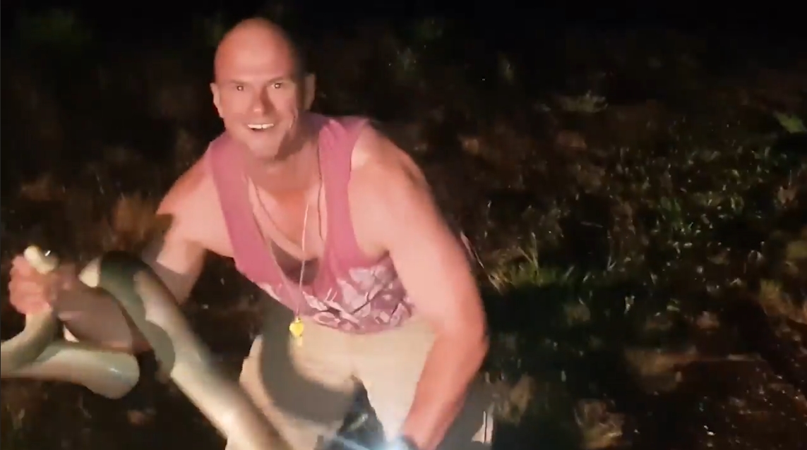 도로 위에 나타난 뱀을 잡고 야생으로 돌려 보내기 전에 힘자랑 하는 남성의 모습(유튜브 영상 캡처)