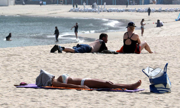 전국적으로 무더운 날씨를 보인 15일 오후 부산 서구 송도해수욕장에서 관광객들이 태닝을 하고 있다. 이날 경남 밀양이 32.6도를 기록하는 등 전국적으로 7월 여름 더위가 이어졌다.  연합뉴스