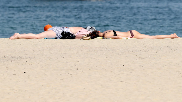 전국적으로 무더운 날씨를 보인 15일 오후 부산 서구 송도해수욕장에서 관광객들이 태닝을 하고 있다. 이날 경남 밀양이 32.6도를 기록하는 등 전국적으로 7월 여름 더위가 이어졌다.  연합뉴스