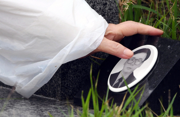 18일 광주 국립 5.18민주묘지에서 열린 ‘제38주년 5.18 민주화 운동 기념식’을 마친 뒤 한 유가족이 고인의 묘 앞에 마련된 사진을 어루만지고 있다. 2018. 05. 18 박윤슬 기자 seul@seoul.co.kr