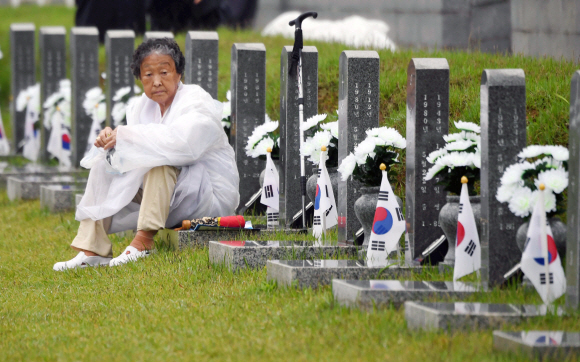 18일 광주 국립 5.18민주묘지에서 열린 ‘제38주년 5.18 민주화 운동 기념식’을 마친 뒤 한 유가족이 고인의 묘 앞에서 앉아 고인을 떠올리고 있다. 2018. 05. 18 박윤슬 기자 seul@seoul.co.kr