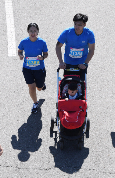 19일 서울 상암동 월드컵공원에서 열린  제17회 서울신문 하프마라톤대회’에 참가한 한 부부가 아이를 유모차에 태우고 달리고  있다 2018.5.19 이호정 전문기자 hojeong@seoul.co.kr