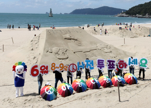 20일 부산 해운대해수욕장에서 열린 2018 해운대모래축제에서 부산시 선관위 관계자들이 지방선거 투표 참여 홍보를 위해 만든 대형 모래작품 앞에서 캠페인을 하고 있다. 2018.5.20  연합뉴스