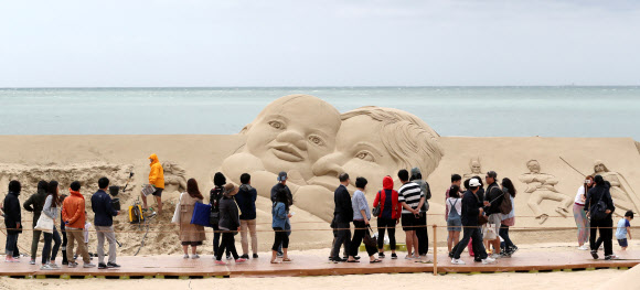 20일 부산 해운대해수욕장에서 열린 2018 해운대모래축제에서 시민들이 대형 모래작품을 감상하고 있다. 올해로 14회째를 맞은 해운대모래축제는 ‘Hero(영웅), 모래로 만나다’를 주제로 22일까지 열린다.  연합뉴스