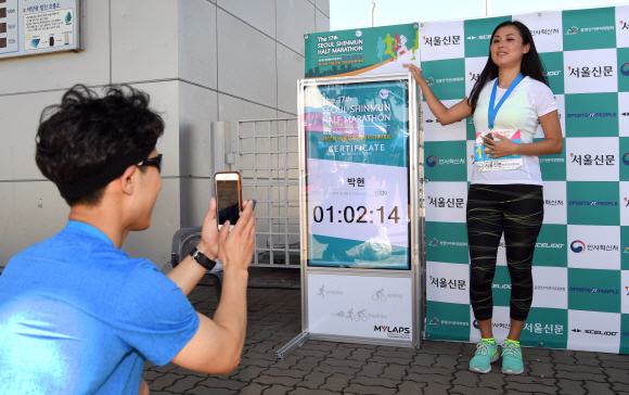 1시간2분14초의 기록으로 결승선을 밟은 여성 참가자가 자신의 기록이 입력된 전광판 옆에서 인증 사진을 찍고 있다. 정연호 기자 tpgod@seoul.co.kr