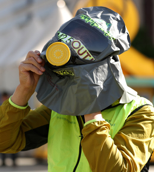 23일 오전 서울 광화문사거리에서 열린 대중교통 이용 및 차량2부제 참가 독려 캠페인에서 방독면을 쓴 참가자가 통화를 하고 있다. 2018.5.23  연합뉴스