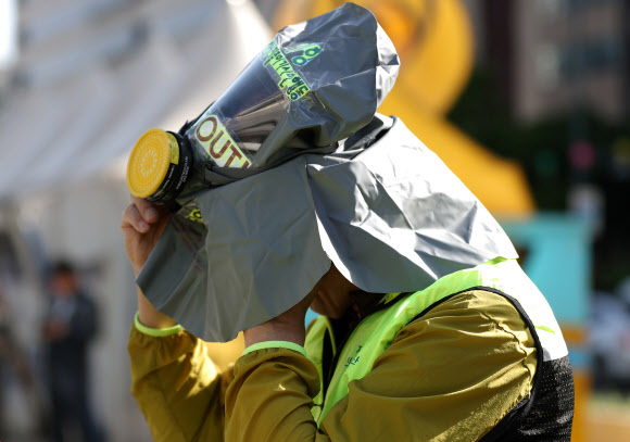 23일 오전 서울 광화문사거리에서 열린 대중교통 이용 및 차량2부제 참가 독려 캠페인에서 방독면을 쓴 참가자가 통화를 하고 있다. 2018.5.23  연합뉴스