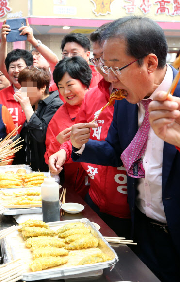 6·13 지방선거 지원 유세차 충북 제천을 찾은 자유한국당 홍준표 대표(오른쪽)가 23일 오후 제천의 한 전통시장에서 음식을 맛보고 있다. 2018.5.23  연합뉴스