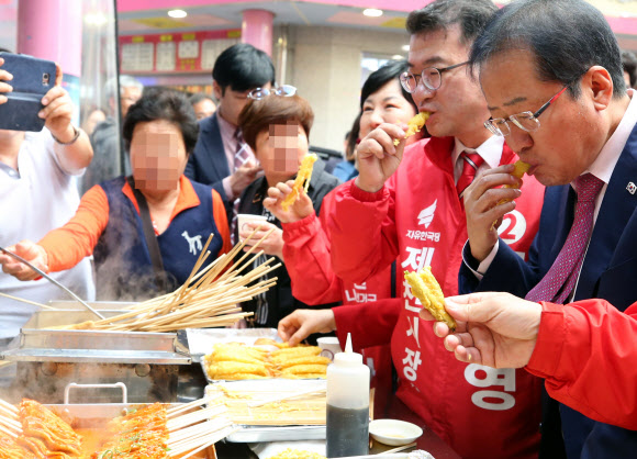 6?13 지방선거 지원 유세차 충북 제천을 찾은 자유한국당 홍준표 대표(오른쪽)가 23일 오후 제천의 한 전통시장에서 음식을 맛보고 있다. 2018.5.23  연합뉴스