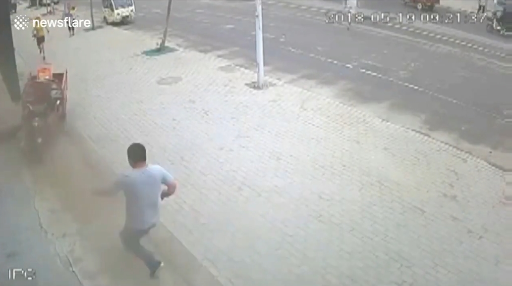 삼륜차 옆에 매달려 있는 아이를 구하기 위해 몸을 던져 막은 한 중국 남성의 영웅적 모습(유튜브 영상 캡처)