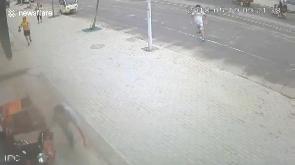 삼륜차 옆에 매달려 있는 아이를 구하기 위해 몸을 던져 막은 한 중국 남성의 영웅적 모습(유튜브 영상 캡처)