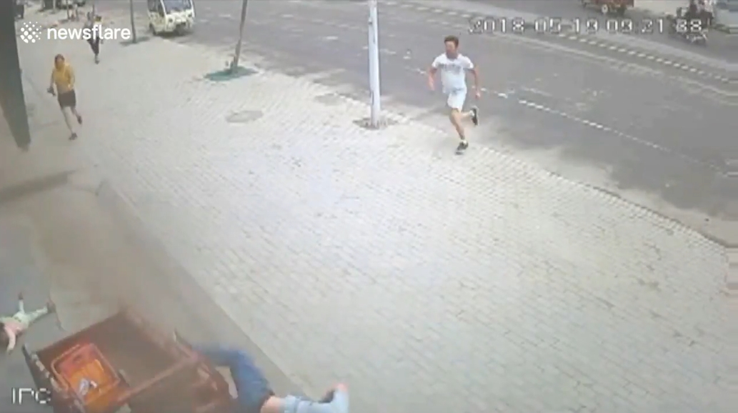 삼륜차 옆에 매달려 있는 아이를 구하기 위해 몸을 던져 막은 한 중국 남성의 영웅적 모습(유튜브 영상 캡처)