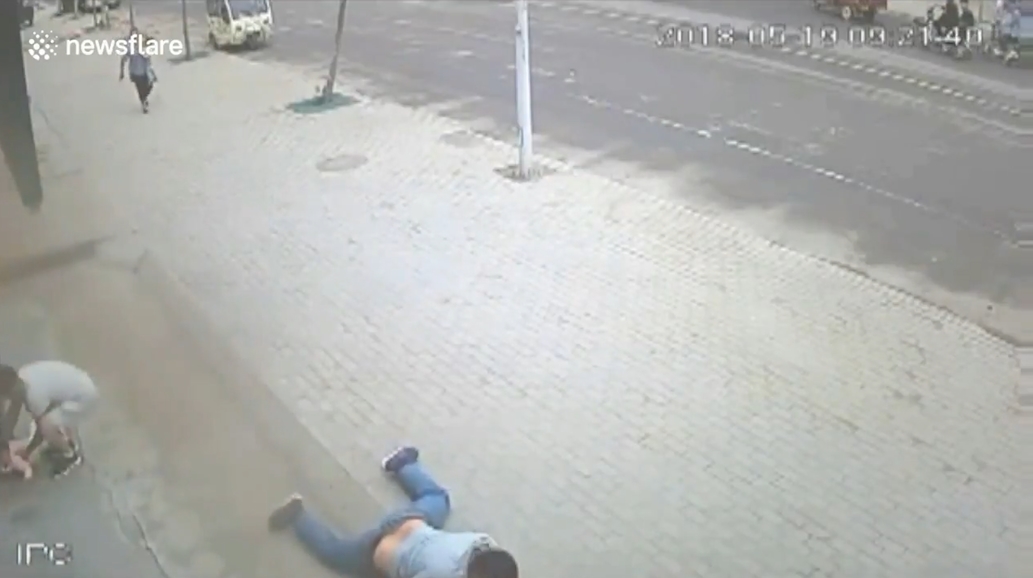 삼륜차 옆에 매달려 있는 아이를 구하기 위해 몸을 던져 막은 한 중국 남성의 영웅적 모습(유튜브 영상 캡처)