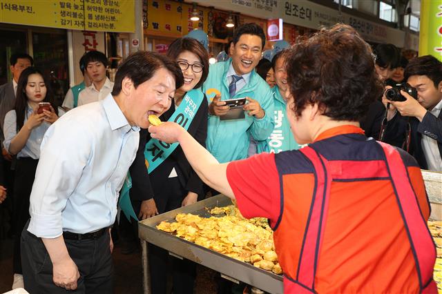 안철수 바른미래당 서울시장 후보가 1일 오전 서울 관악구 신원시장을 방문해 한 상인이 건네주는 전을 먹고 있다. 2018.6.1 뉴스1