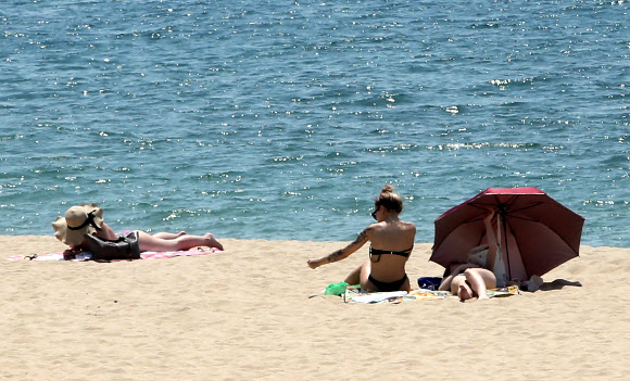 1일 문을 연 부산 해운대해수욕장에서 외국인들이 일광욕을 즐기고 있다. 송정·송도 해수욕장도 한 달 일찍 이날 문을 열었고 광안리 ·다대포·일광·임랑해수욕장은 7월 1일 공식 개장한다. 2018.6.1  연합뉴스