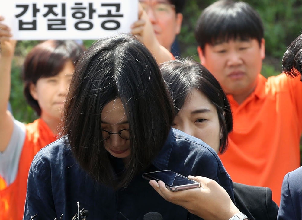 조현아 전 대한항공 부사장이 4일 오전 밀수·탈세 혐의에 대해 조사를 받기 위해 인천본부세관에 출석하며 취재진의 질문을 받고 있다. 그의 뒤에서 민중당 인천시당 당원들이 한진그룹 일가의 갑질을 규탄하는 피켓을 들고 있다. 2018.6.4 연합뉴스