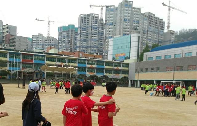서울 은평구 은평초등학교 뒤편으로 녹번 1,2단지 재개발 공사가 한창인 가운데 운동장에 나온 학생들이 마스크를 쓴 채 공사 현장을 바라보고 있다.  학부모 제공