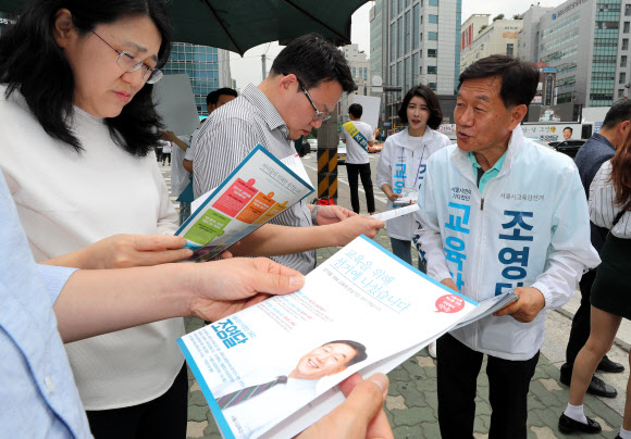 조영달 서울교육감 후보가 8일 서울 서초구 서울교대 인근 횡단보도 앞에서 녹색 신호를 기다리는 시민들에게 자신의 공약 등이 담긴 선거 유인물을 나눠주고 있다.  연합뉴스