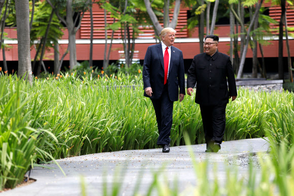 지난 12일 북·미 정상회담을 위해 만난 도널드 트럼프(왼쪽) 미국 대통령과 김정은(오른쪽) 북한 국무위원장이 업무 오찬 이후 카펠라호텔 주변을 산책하는 모습. 싱가포르 로이터 연합뉴스
