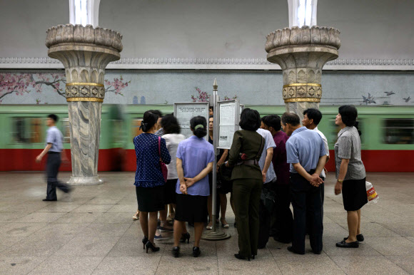 북한 평양의 통근 시민들이 13일 한 지하철역 승강장에 설치된 신문게시대로 몰려들어 12일 싱가포르에서 열린 북미정상회담 소식이 실린 신문을 읽고 있다. 2018.6.13  AFP 연합뉴스