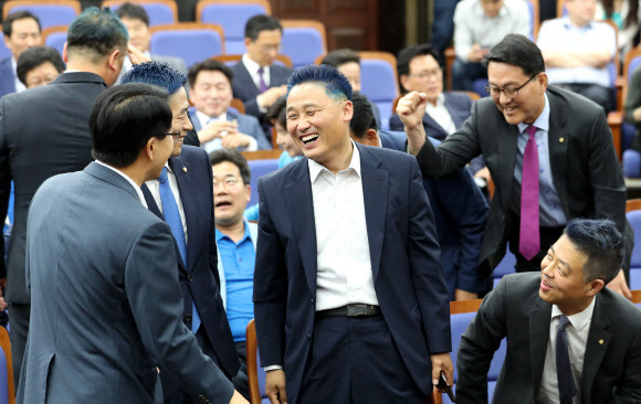 14일 오후 국회에서 열린 더불어민주당 의원총회에서 짧고 파란색으로 머리를 염색한 김영진 의원(가운데)이 동료의원과 대화하며 환하게 웃고 있다. 이들은 6.13 지방선거 투표율이 60%를 넘을 경우 머리를 짧게 깎고 파란색 염색을 하겠다고 공약한 바 있다. 2018.6.14 연합뉴스