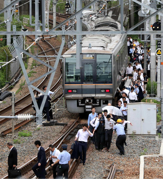 18일 오전 일본 오사카에서 지진이 발생한 가운데 지진으로 멈춰 선 열차에서 승객들이 빠져나와 철길을 걷고 있다. 이번 지진은 규모 5.9로 추정된다고 일본 기상청은 밝혔다.  AFP 연합뉴스