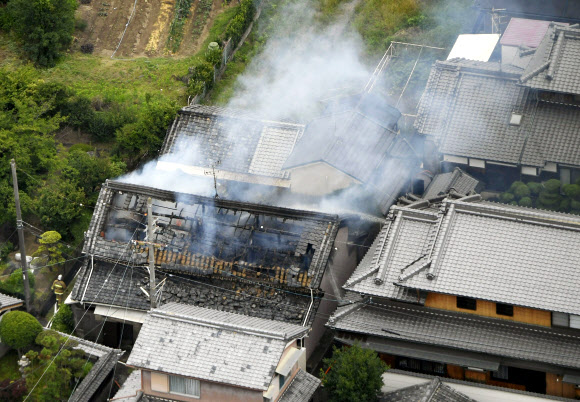 18일 오전 일본 오사카에서 규모 5.9로 추정되는 지진이 발생한 가운데 다카쓰키시에 위치한 한 가옥이 불에 타 연기가 피어오르고 있다.  AP 연합뉴스