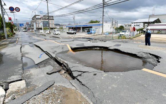 18일 오전 일본 오사카에서 규모 5.9의 지진이 발생한 가운데 다카쓰키시의 도로 일부가 내려앉아 움푹 팬 자리에 물이 고여있다. AP 연합뉴스