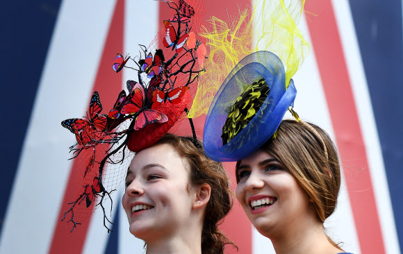 21일(현지시간) 영국 잉글랜드 버크셔카운티 애스컷에서 열린 ‘여성의 날(Ladies Day)’로 알려진 ‘로얄 애스컷 경마 대회(the Royal Ascot horse race meeting)’ 셋째 날에 관람을 하려는 여성들이 화려한 모자를 쓰고 포즈를 취하고 있다. EPA 연합뉴스