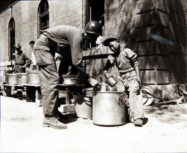 1950년 9월 23일 한 소년이 퍼 주는 커피를 미군이 받고 있다.  국사편찬위원회 제공
