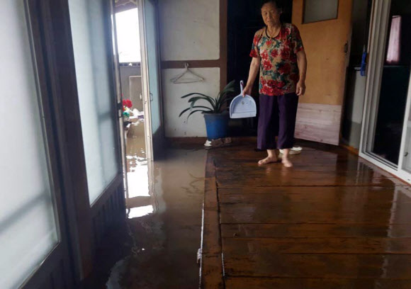 장맛비가 내린 28일 오전 전남 해남군 문내면 선두마을 한 주민이 안방까지 차오른 물을 걷어내며 허탈한 표정을 짓고 있다. 2018.6.28  해남군 제공=연합뉴스