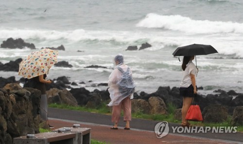 27일 오전 제주 서귀포시 범섬 앞 해안도로에서 관광객들이 우비와 우산으로 장맛비를 피하고 있다. 2018.6.27 연합뉴스