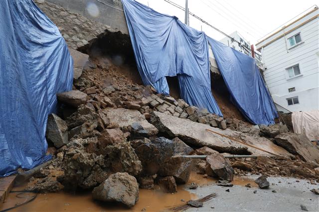 장마전선의 영향으로 남부지역 곳곳에 호우경보가 발령된 28일 오전 7시 30분경 부산 영도 흰여울마을 동삼방면 오르막 우측 해안가 옹벽이 폭우로 무너져 내려 인근 도로진입이 통제되고 있다. 이 현장은 3층 건물 신축을 위해 기초공사가 진행되고 있는 곳이다. 2018.6.28 뉴스1