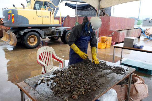 28일 전남 목포신항 부두에서 작업자가 세월호 선체 내부 진흙덩이를 조사하며 미수습자 흔적을 찾고 있다. 2018.6.28  연합뉴스