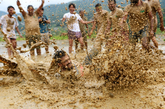 네팔의 젊은이들이 29일(현지시간) 카트만두 외곽의 레 마을(Lele village)의 논에서 즐거운 시간을 보내고 있다. 네팔의 농부들은 매년 모내기 시즌이 시작되면 ‘National Paddy Day’를 기념하고 있다. AFP 연합뉴스