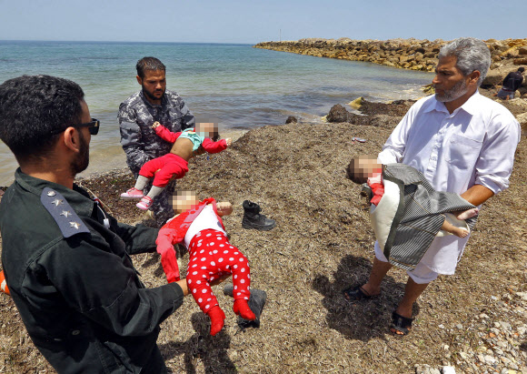 지난달 29일(현지시간) 리비아 수도 트리폴리 동쪽 해변에서 숨진 채 발견된 난민 아기들이 지역 주민과 보안군 품에 안겨 있다. 지중해와 맞닿아 있는 리비아 북부 연안에서 난민들이 탑승한 고무보트가 난파하면서 100여명이 실종됐다.  트리폴리 AFP 연합뉴스