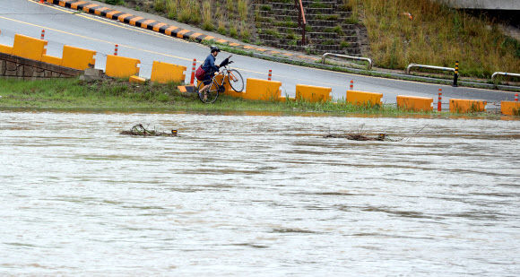 대전과 충남지역에 밤새 많은 비가 내린 2일, 대전 갑천변 자전거길을 지나던 한 출근길 시민이 물을 피해 도로로 나가고 있다. 2018.7.2  연합뉴스